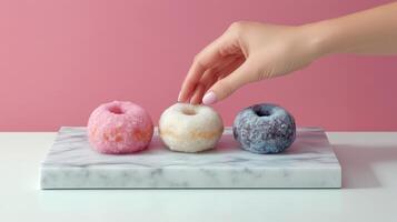 Colorful assortment of donuts on a marble platter with a hand reaching for one photo