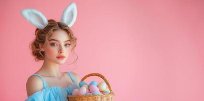 Young woman wearing bunny ears holds a basket of colorful eggs against a pink background photo