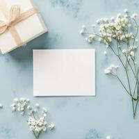 Gift box and blank card with delicate flowers on a blue background for special occasions photo
