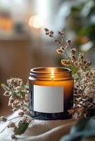Warm amber candle flickering beside dried flowers in a cozy indoor setting photo