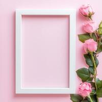 Elegant white frame with soft pink roses on pastel pink background photo