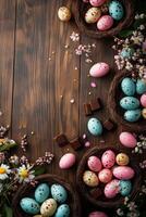 Colorful Easter eggs and chocolate on wooden table surrounded by flowers and nesting materials photo
