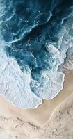Waves crashing on sandy beach with vibrant turquoise water and gentle foam at shoreline photo