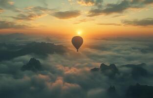 Hot air balloon floats above mountains at sunrise with clouds surrounding the landscape photo