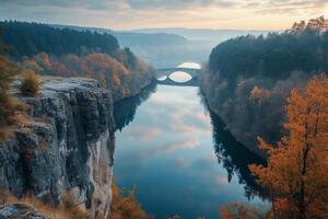 Autumn landscape with bridge over river at sunrise in a picturesque valley photo