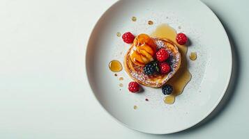 Delicious stack of pancakes topped with fresh fruits and syrup served on a white plate photo