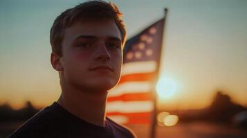 Young man standing near American flag at sunset with warm tones in the background photo