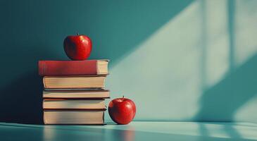 Stacked books with red apples on a teal background illuminated by soft sunlight in a cozy setting photo