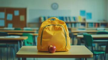 Bright yellow backpack with red apple on classroom table during school hours photo