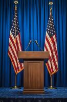 Podium setup with American flags for a formal event in a blue backdrop photo