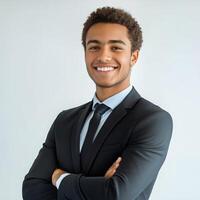 Young professional in a suit smiles confidently while standing against a plain background photo