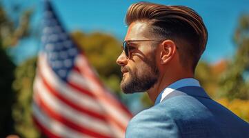 Young man with stylish haircut stands confidently in front of American flag during sunny outdoor event photo