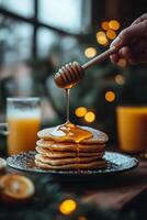 Stack of pancakes with honey drizzling, orange juice nearby in a cozy morning setting photo