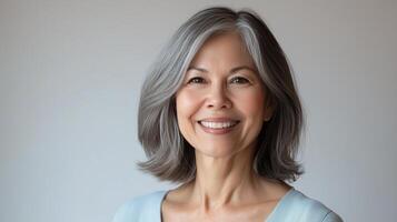 Older woman with gray hair smiling against a neutral background in a warm and inviting setting photo