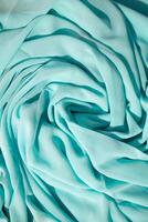 Spiral Twisted Turquoise wavy crumpled fabric with little sparkling dust, texture and background. photo