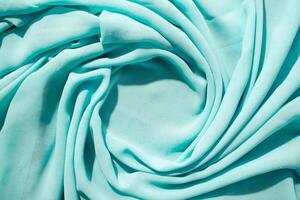 Spiral Twisted Turquoise wavy crumpled fabric with little sparkling dust and copy space in center, abstract background. photo