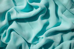 Turquoise wavy crumpled fabric with little sparkling dust, texture and abstract background. photo