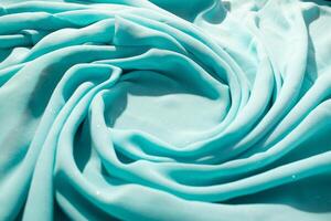 Spiral Twisted Turquoise wavy fabric with little sparkling dust and copy space in center, texture and background. photo