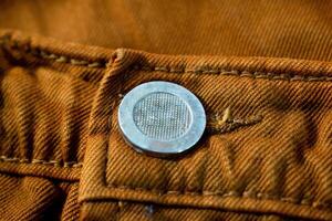 Metallic button on bright brown jeans fabric, background texture mockup photo