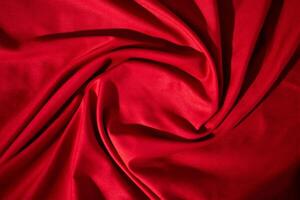 Red fabric wavy spiral crumpled texture with copy space in the center. photo