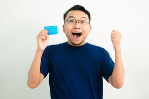Happy asian man Celebrating pose with hold credit card. Banking, Financial concept and fist up gesture. Blue concept photo