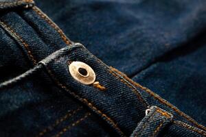 Close up gold and shiny button navy blue jeans fabric texture. photo
