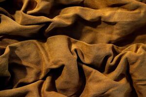 Close up crumpled wavy bright brown jeans fabric background texture. photo