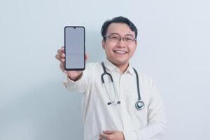 happy Asian man doctor, male nurse Pointing and showing phone at the camera isolated white background. photo