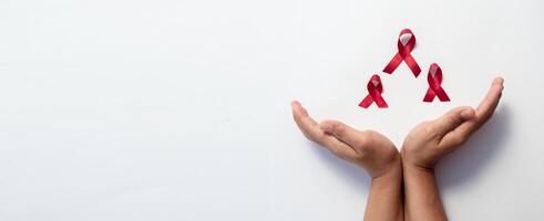 Female hand covering and protect pose red ribbon, HIV awareness concept, world AIDS day, world cancer day isolated background. photo