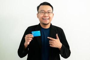 Happy asian man hold and pointing credit card. Banking, Financial isolated concept. photo