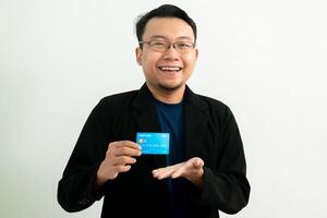 Smiling asian businessman hold credit card and showing gesture. Banking, Financial isolated background, blue color concept. photo