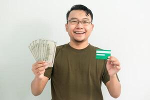 Joyful asian man hold credit card and money. Banking, Financial isolated background, green color concept. photo