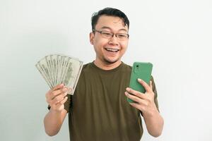 Happy asian man hold Money and phone. Banking, Financial and technology isolated background, green color concept. photo