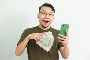 Delighted asian man hold and pointing Money and phone. Banking, Financial and technology isolated background, green color concept. photo
