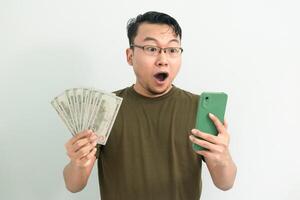 Surprised asian man hold Money and phone. Banking, Financial and technology isolated white background photo