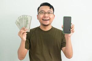 Happy asian man hold Money and showing phone screen. Banking, Financial and technology isolated background, green color concept. photo