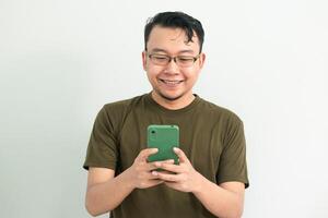 Smiling Asian man looking at phone. portrait isolated background, green color concept. photo