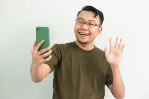 Happy Asian man doing call and say hi at phone. portrait isolated background, green color concept. photo