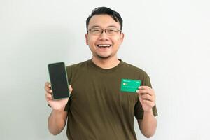 Delighted asian man hold credit card and phone. Banking, Financial and technology isolated white background photo