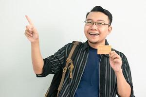 Cheerful asian student hold credit card with pointing gesture. Banking, Financial isolated concept. photo