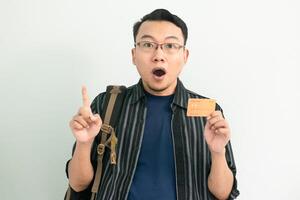Surprised asian student hold credit card with pointing gesture. Banking, Financial isolated concept. photo