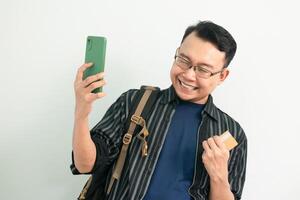 Happy asian Student hold credit card and phone with celebrating pose. Banking, Financial and technology isolated background photo