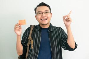 Smiling asian student hold credit card with pointing gesture. Banking, Financial isolated concept. photo