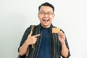 Cheerful asian student hold and pointing credit card gesture. Banking, Financial isolated concept. photo