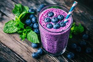 Blueberry smoothie in glass with fresh berries on wooden background photo