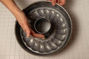Baker greasing fluted tube pan with butter, getting ready to bake photo