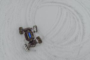 Radio-controlled car leaving tracks on fresh snow during winter day photo