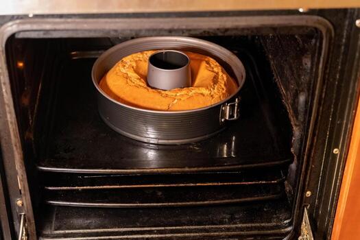 Round cake baking in a circular mold inside an oven photo