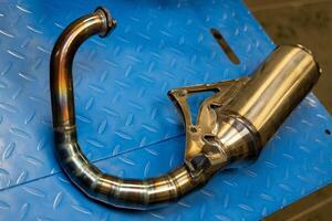 Motorcycle exhaust pipe resting on blue metal surface photo