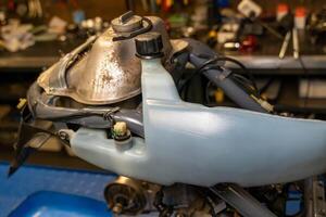 Mechanic replacing fuel tank of motorcycle in workshop photo
